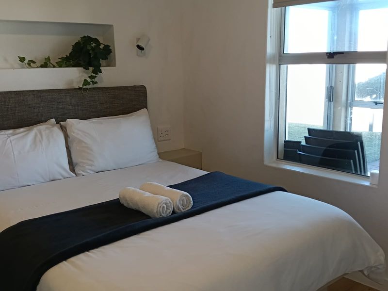 A cozy bedroom featuring a built-in wall niche, a large sliding window providing natural light, and neutral finishes.