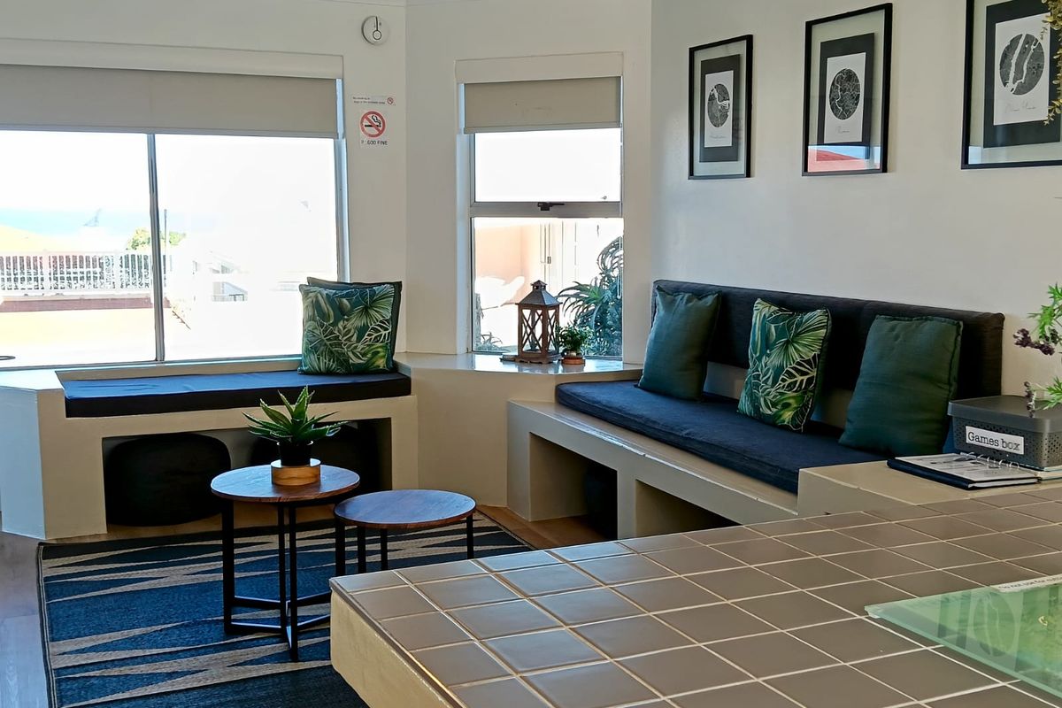 A bright living area featuring built-in bench seating, tiled counter space, and large windows with roller blinds, offering a functional and comfortable layout.
