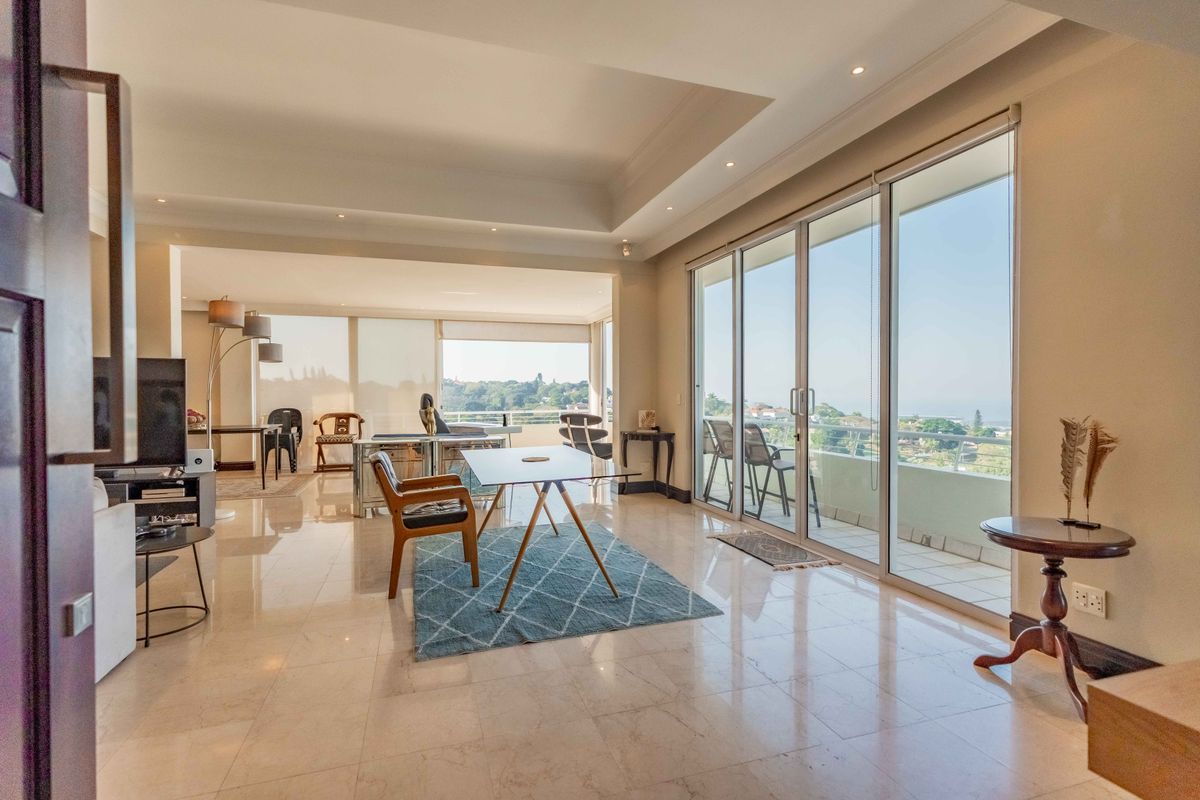 Spacious living area featuring polished marble flooring, recessed ceiling with downlights, and large sliding glass doors providing seamless access to the balcony.
