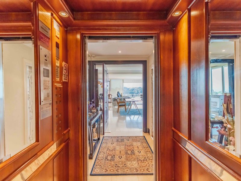Private elevator entrance featuring rich wood paneling, recessed lighting, and polished marble flooring, providing direct access into the penthouse living area.