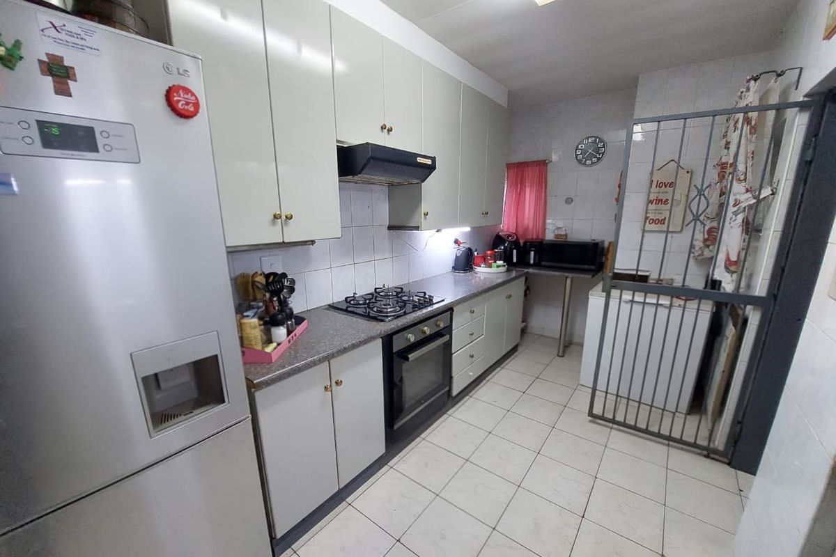 Functional kitchen featuring built-in cabinetry, gas hob, oven, extractor fan, and tiled flooring, offering a practical layout for daily meal preparation.