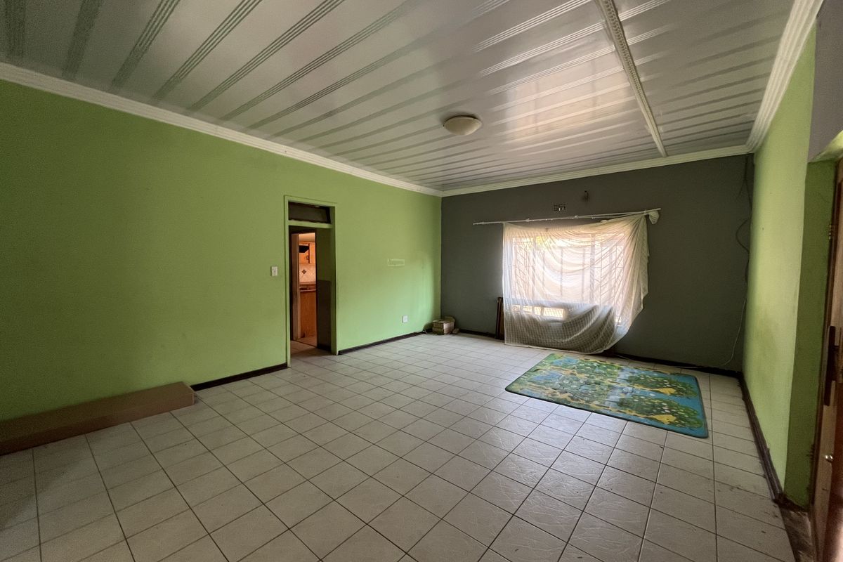 An empty living room featuring tiled flooring and a panelled ceiling, offering a blank canvas for renovation and interior design updates.