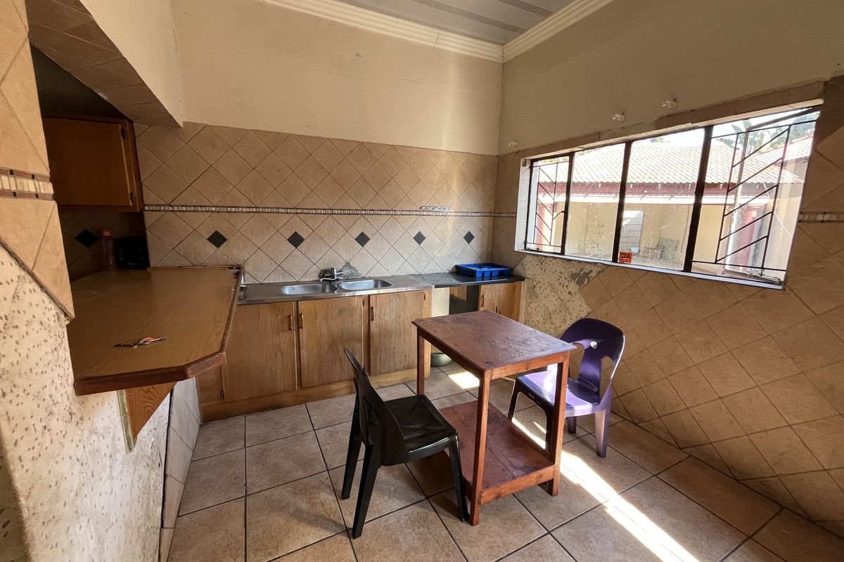 A dated kitchen featuring wooden cabinetry, tiled splashbacks, and tiled flooring, requiring cosmetic updates to modernize the space.