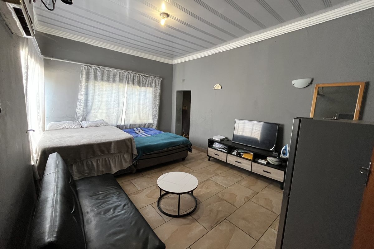 A bedroom featuring tiled flooring, coved ceilings, and an integrated air conditioning unit, requiring cosmetic updates to the wall finishes.