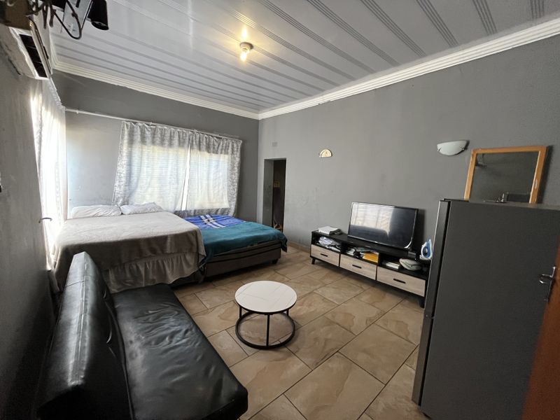 A bedroom featuring tiled flooring, coved ceilings, and an integrated air conditioning unit, requiring cosmetic updates to the wall finishes.