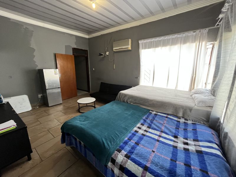 A bedroom featuring tiled flooring, an air conditioning unit, and visible wall surface imperfections requiring cosmetic attention.