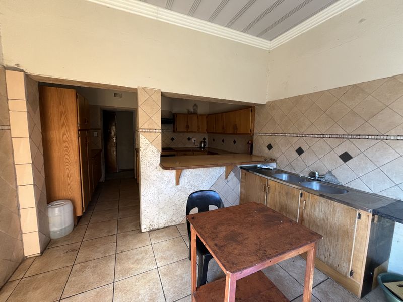 A dated kitchen featuring wooden cabinetry, a breakfast bar, and tiled backsplash, offering potential for modernization and renovation.