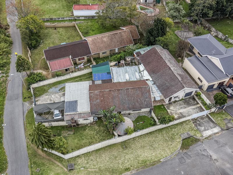 Aerial view of the property showing the main dwelling, tiled roof structure, boundary walls, and surrounding garden area.