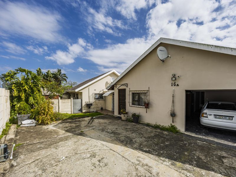 Front exterior view of the property featuring a concrete driveway, garage access, and perimeter wall with security fencing.