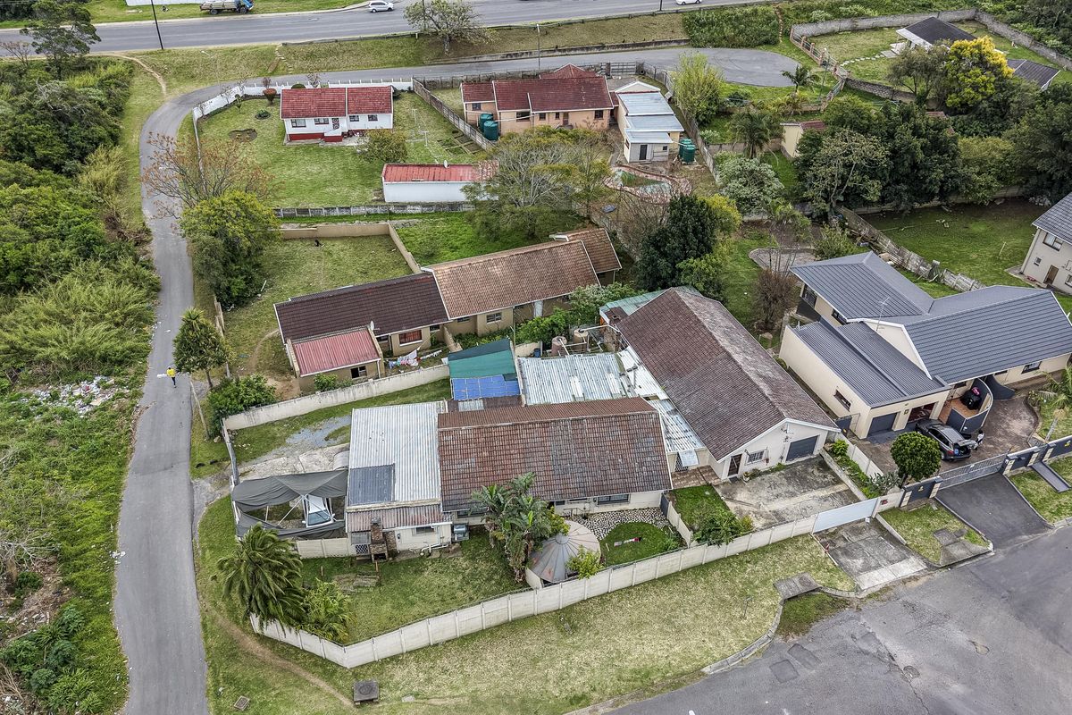 Aerial view of the residential property showing the main house, outbuildings, boundary walls, and surrounding garden area.