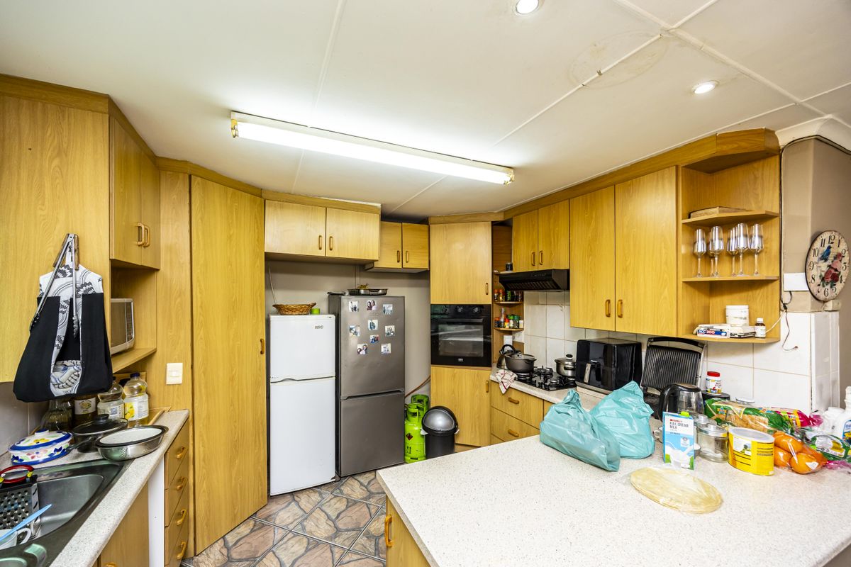 A functional kitchen featuring laminate cabinetry, built-in oven, gas hob, and stone-look floor tiles, offering a practical layout with ample storage space.