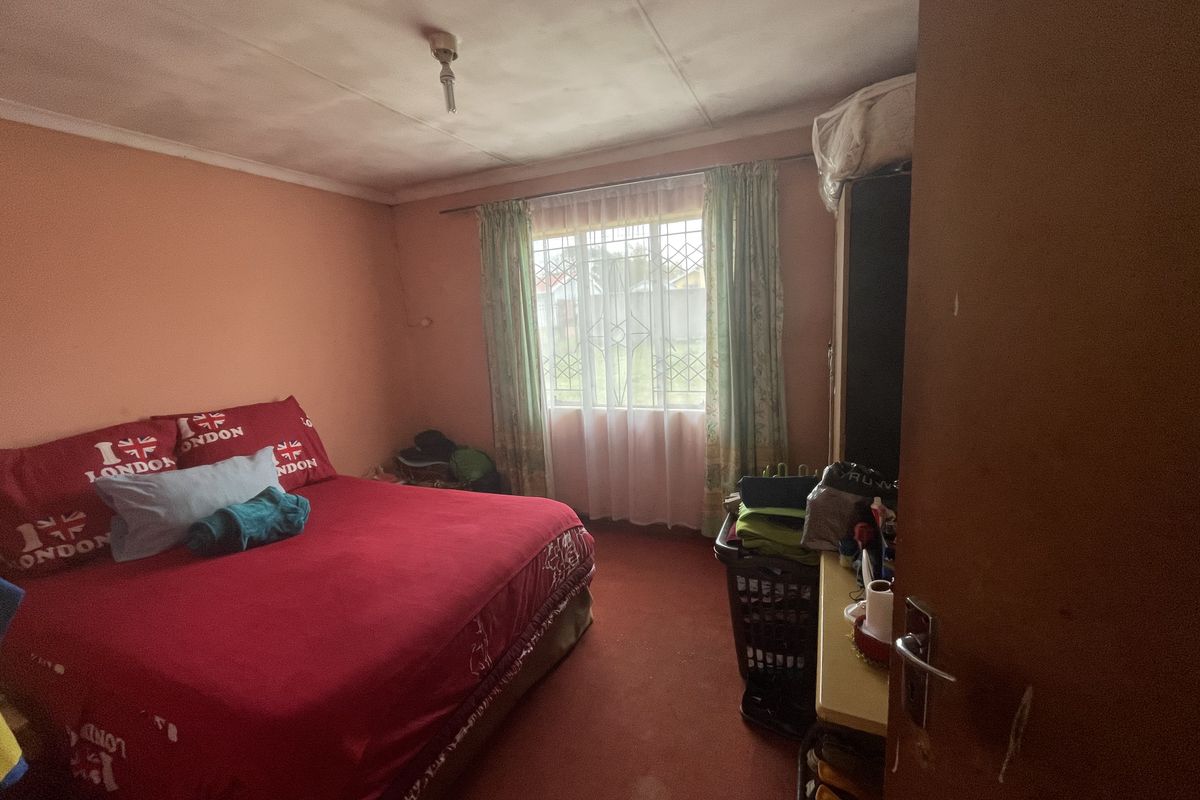 A bedroom featuring a window with a security gate and curtain rod, requiring cosmetic updates to the walls and ceiling.