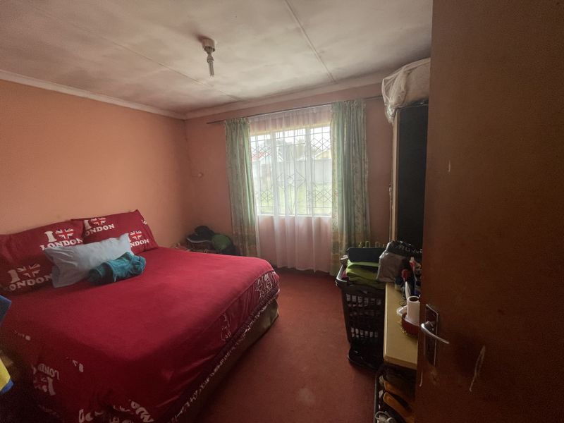 A bedroom featuring a window with a security gate and curtain rod, requiring cosmetic updates to the walls and ceiling.