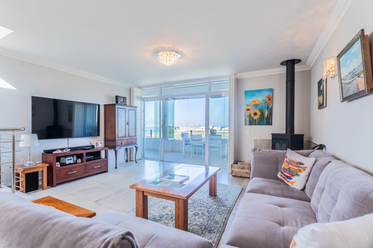 Spacious living room featuring a freestanding fireplace, tiled flooring, and large sliding glass doors that open onto an outdoor patio area.
