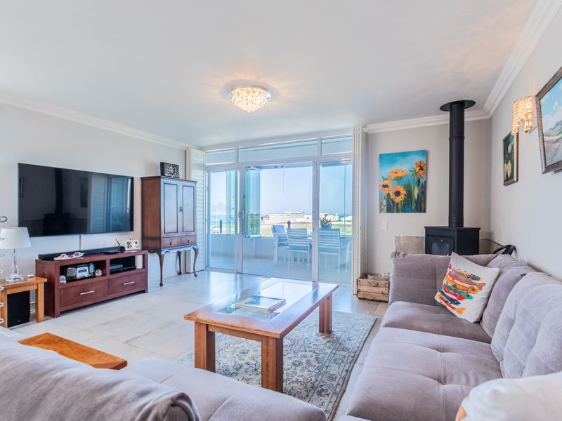 Spacious living room featuring a freestanding fireplace, tiled flooring, and large sliding glass doors that open onto an outdoor patio area.