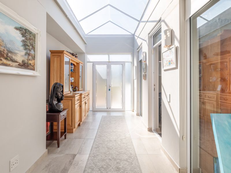 Bright and airy hallway featuring a large skylight, tiled flooring, and glass panel double doors leading to the exterior.
