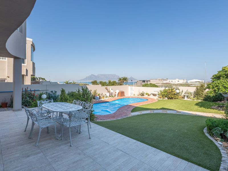 A well-maintained outdoor entertainment area featuring a tiled patio, swimming pool, and landscaped garden with scenic mountain views.