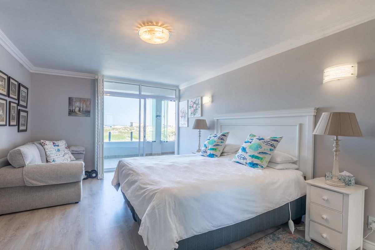 Spacious bedroom featuring light laminate flooring, crown molding, and a large sliding glass door providing access to an outdoor balcony area.