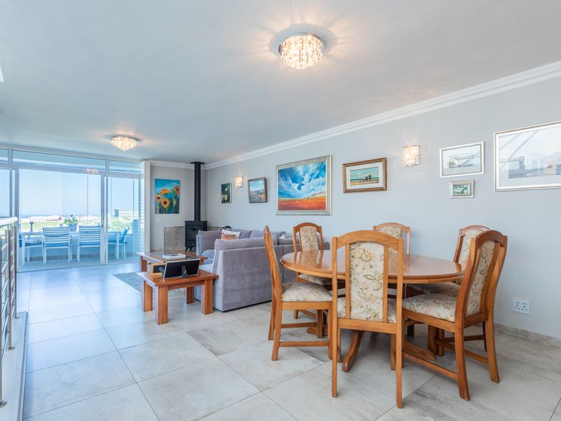 Spacious open-plan living and dining area featuring tiled floors, a modern fireplace, and large sliding doors leading to an outdoor patio.