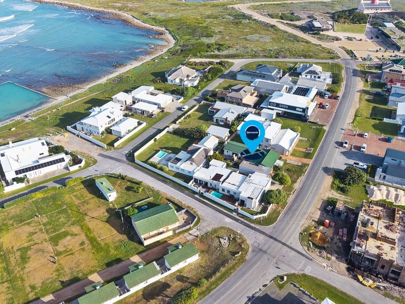 An aerial view of a coastal residential neighborhood, highlighting the property's location near the ocean and local infrastructure.