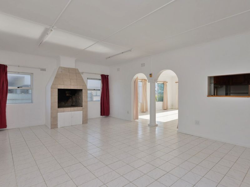 Spacious living area featuring tiled flooring, a built-in fireplace, and an open-plan layout with an archway leading to an adjacent room.