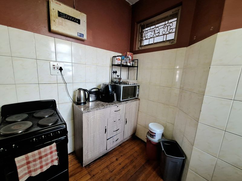 A compact kitchen area featuring tiled splashbacks, built-in cabinetry with stone countertops, and a security-grille window.