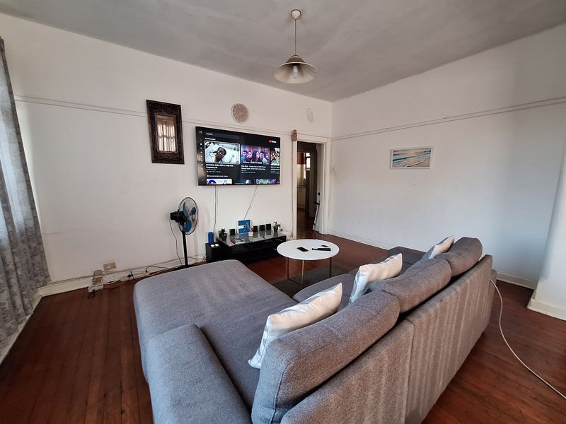 A living room featuring original hardwood flooring and classic picture rails, offering a blank canvas for potential cosmetic updates and interior design improvements.