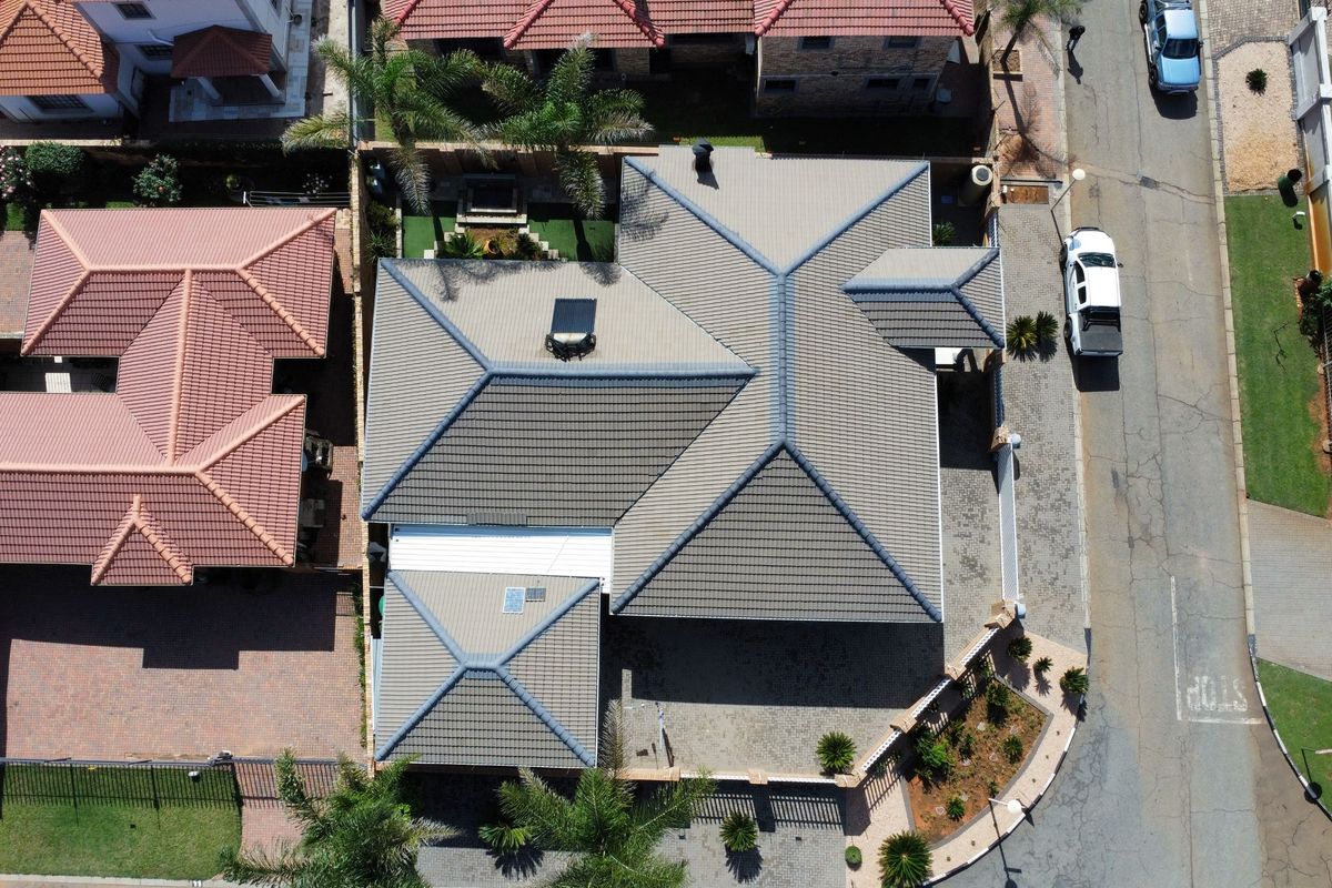 Aerial view of the property showcasing the tiled roof structure, paved driveway, and surrounding boundary walls within the residential estate.