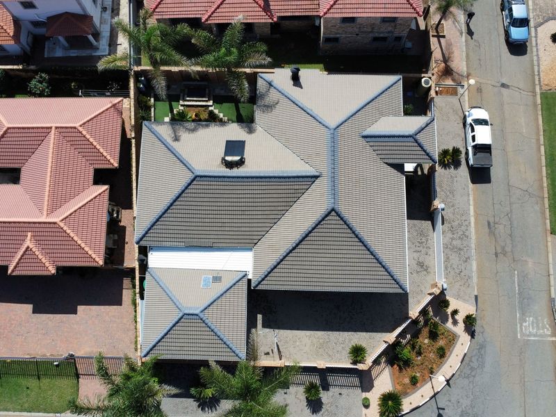 Aerial view of the property showcasing the tiled roof structure, paved driveway, and surrounding boundary walls within the residential estate.