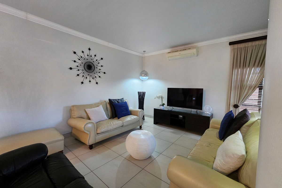 A comfortable living room featuring tiled flooring, a wall-mounted split-system air conditioner, and neutral wall finishes.