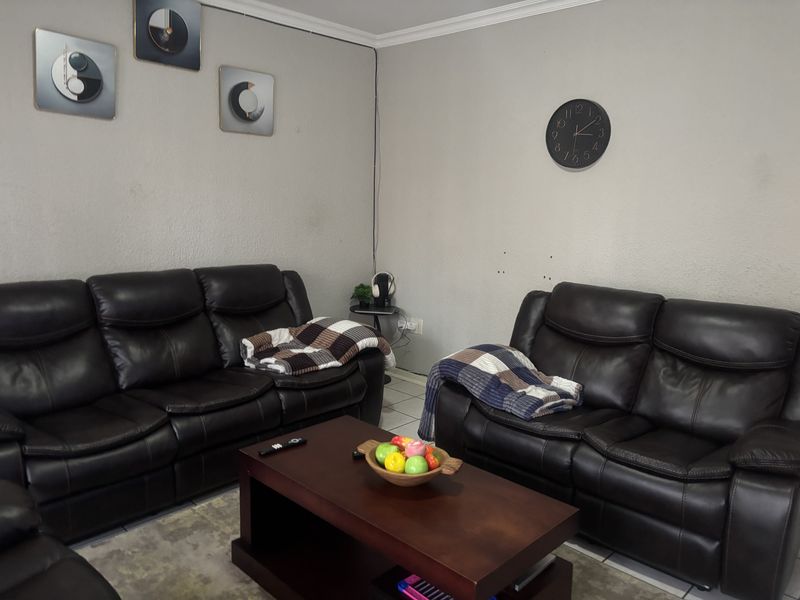 A living room area featuring tiled flooring and coved ceilings, currently presented with a neutral wall finish.