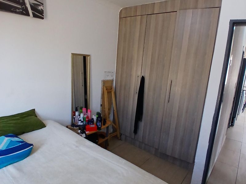 A bedroom featuring tiled flooring and a modern built-in wardrobe with wood-grain finish.