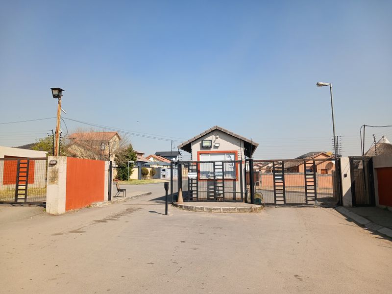 The property entrance features a secure gated access point with a dedicated guard house and perimeter security fencing.