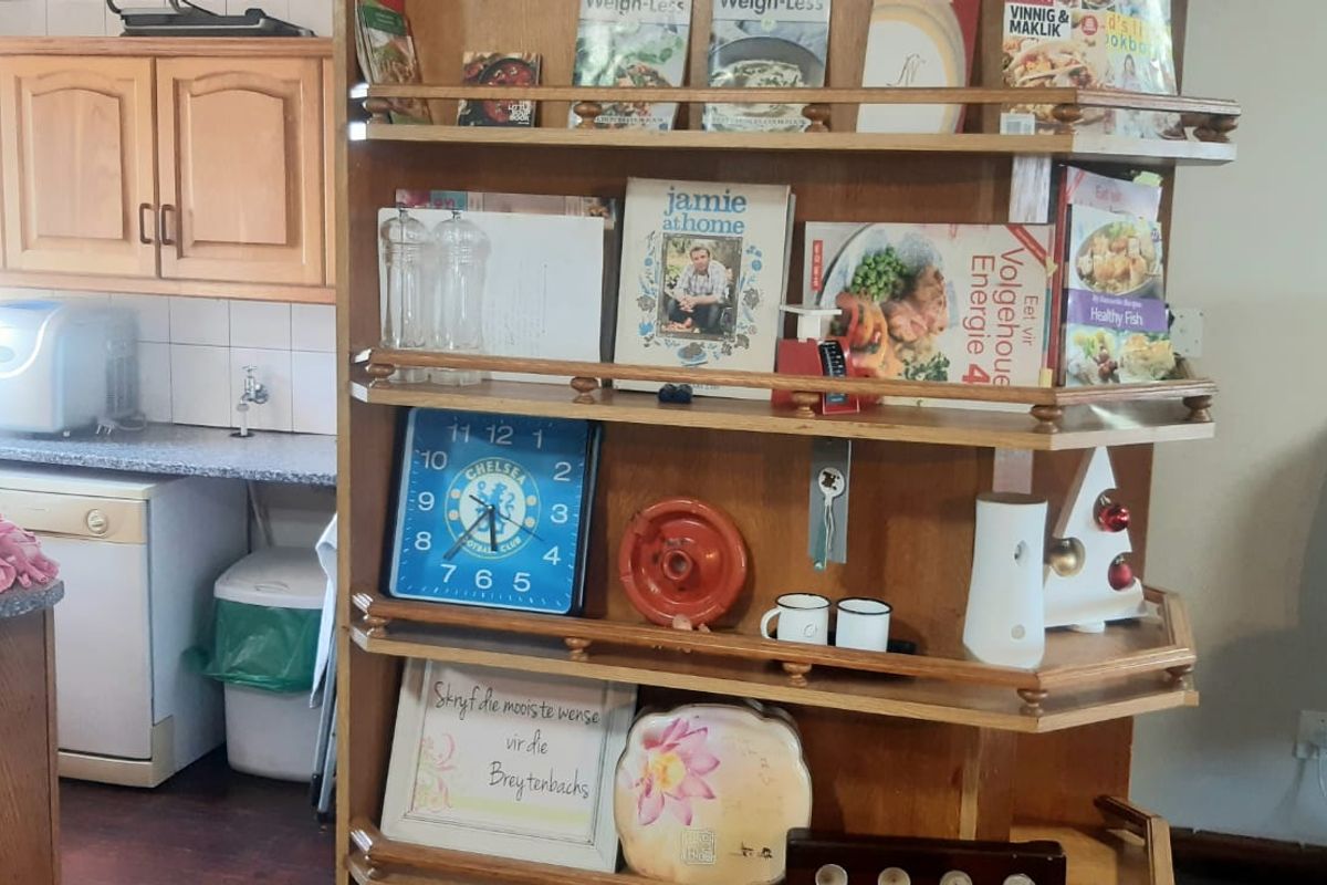 A kitchen area featuring traditional wooden cabinetry, laminate countertops, and a prominent built-in wooden shelving unit for storage and display.