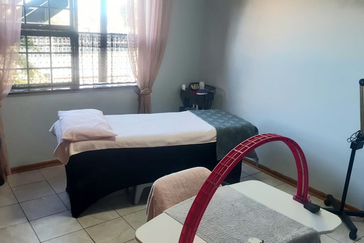 A functional bedroom space featuring tiled flooring and a window, currently utilized as a treatment room.