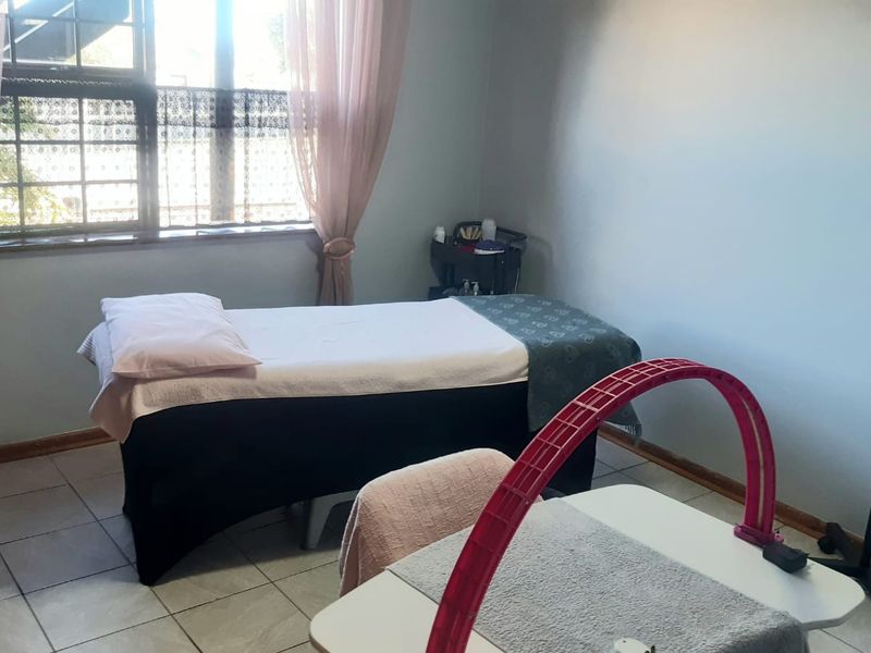 A functional bedroom space featuring tiled flooring and a window, currently utilized as a treatment room.