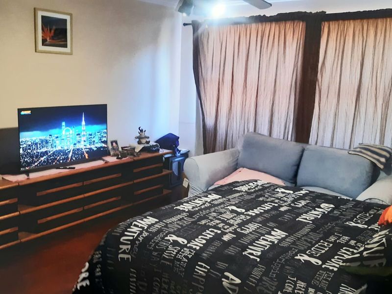 A bedroom featuring a ceiling fan and curtain tracks, currently showing signs of wear including exposed electrical wiring on the wall.
