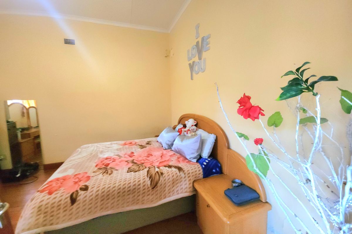 A bedroom featuring yellow painted walls and wooden flooring, providing a functional sleeping space with basic architectural finishes.