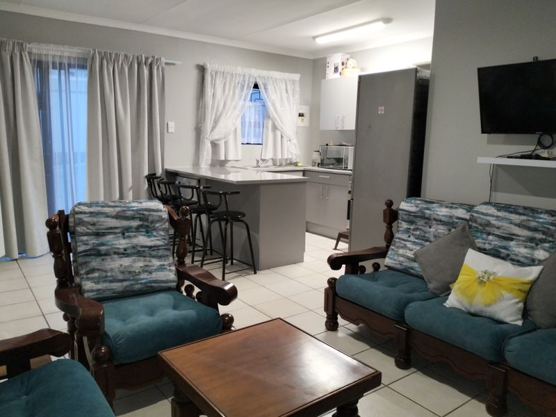 Open plan living area featuring a functional kitchen with island, tiled flooring, and direct access to an outdoor space through a sliding glass door.
