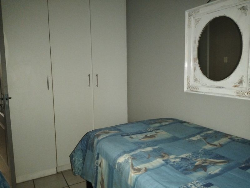 A bedroom featuring built-in cupboards and tiled flooring, providing functional storage space.
