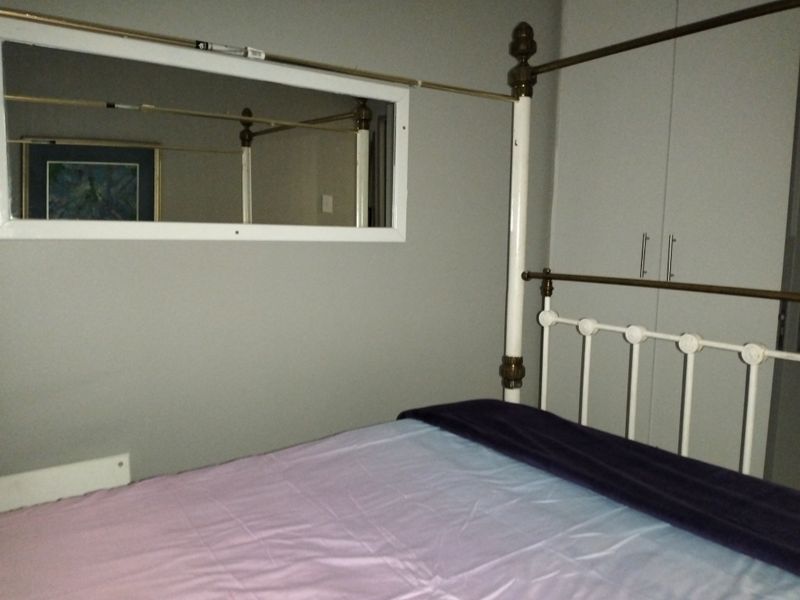 A bedroom featuring built-in cupboards and a wall-mounted mirror, providing functional storage and reflective space.