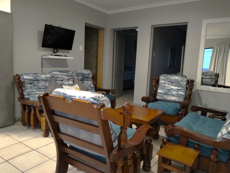 A living room area featuring tiled flooring and multiple internal doorways leading to adjacent rooms.