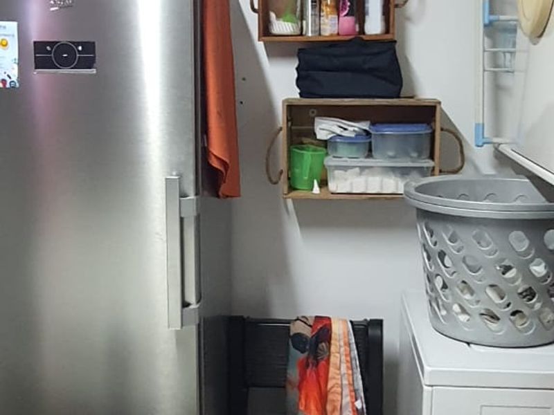 A functional laundry area featuring a wall-mounted drying rack and space for utility appliances.