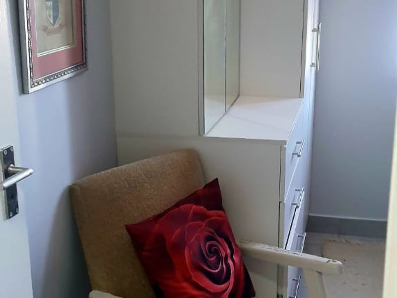 A bedroom corner featuring a white built-in wardrobe with an integrated mirrored vanity unit and neutral wall finishes.