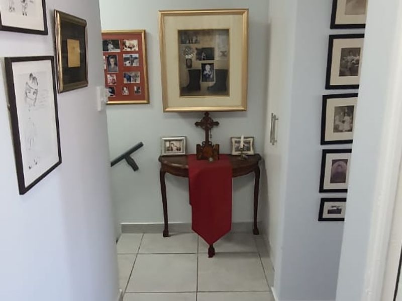A clean and well-maintained hallway featuring neutral tiled flooring and a ceiling access hatch, providing a bright transition space within the townhouse.