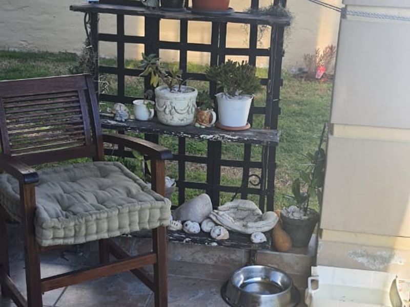 A covered patio area featuring tiled flooring and a structural pillar, providing a functional outdoor space for relaxation.
