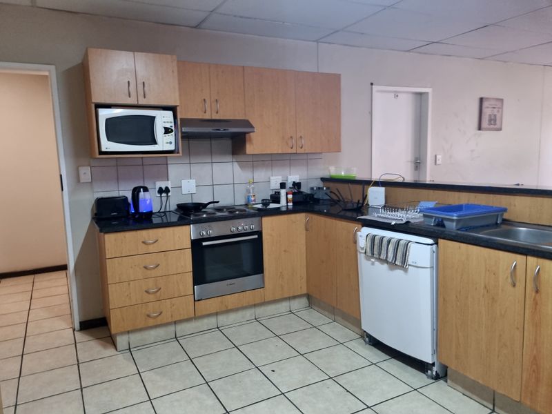 A functional kitchen featuring laminate cabinetry, granite countertops, built-in oven, hob, and extractor fan, with tiled flooring and a drop ceiling.