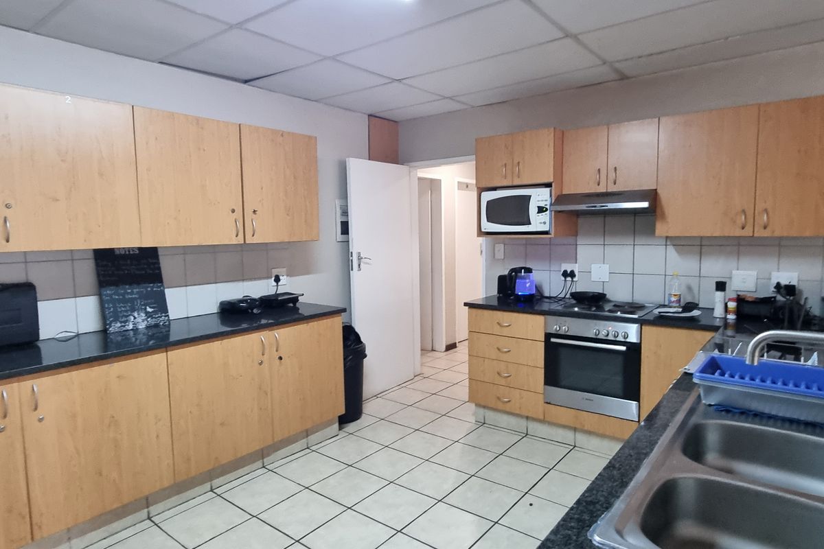 Functional kitchen featuring laminate cabinetry, granite countertops, built-in oven, hob, extractor fan, and tiled flooring with a practical layout.