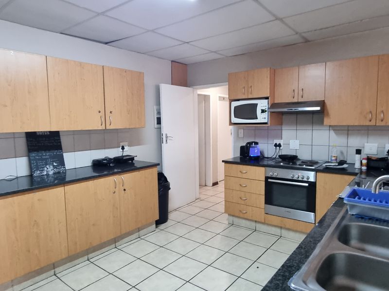 Functional kitchen featuring laminate cabinetry, granite countertops, built-in oven, hob, extractor fan, and tiled flooring with a practical layout.