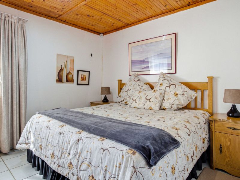 A bedroom featuring a warm timber tongue and groove ceiling and tiled flooring, offering a comfortable and functional living space.